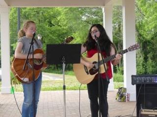 two lovely young ladies playing guitar in the downtown pavilion