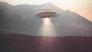 flying saucer hovering in front of a mountain