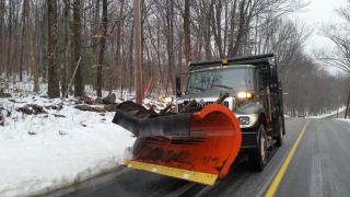 Green town plow truck against snow along side of road
